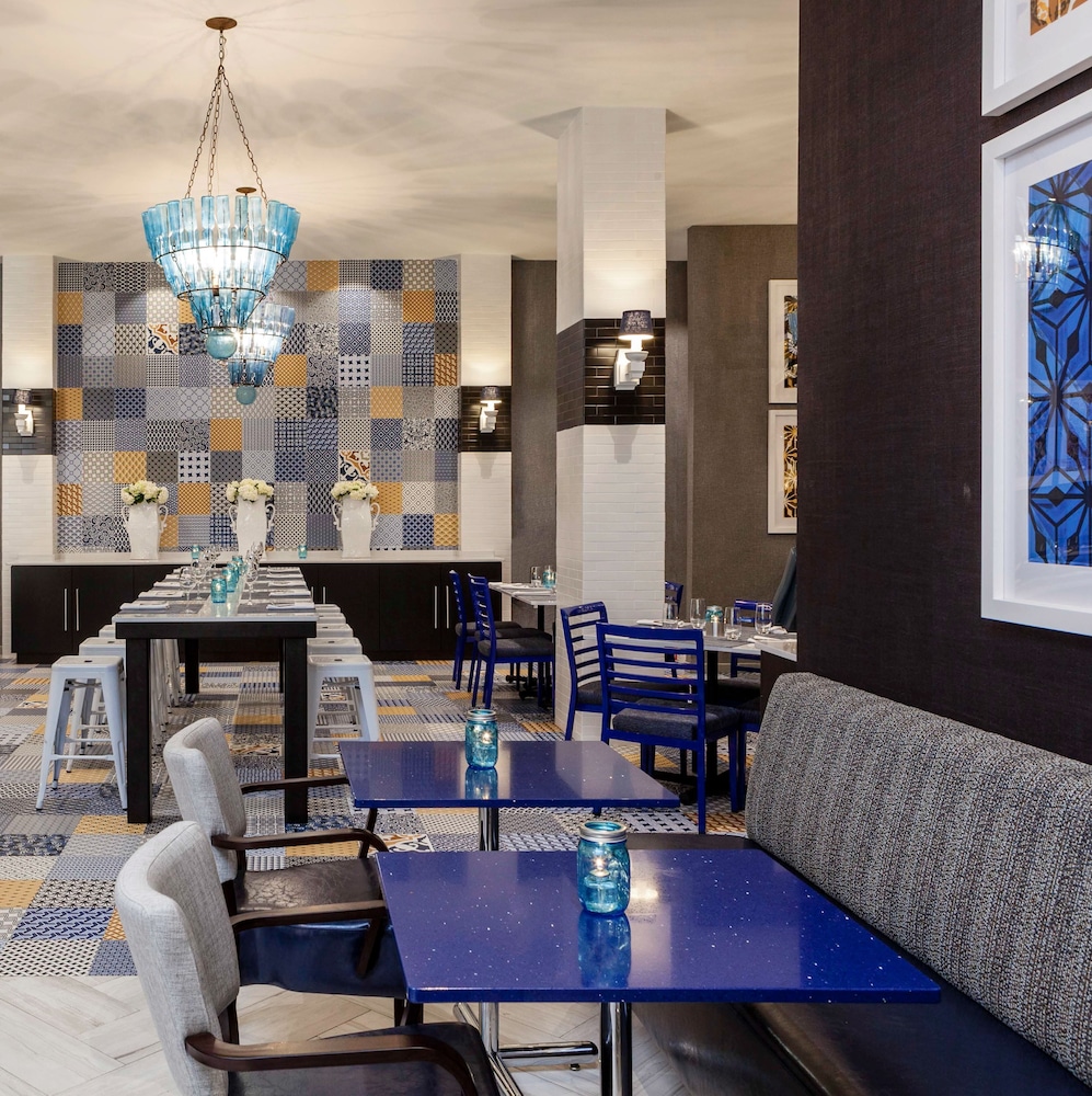 Contemporary dining area at Le Méridien Charlotte with blue tables and patterned wall decor
