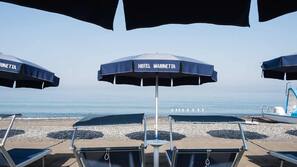 In Strandnähe, Liegestühle, Sonnenschirme, Strandtücher