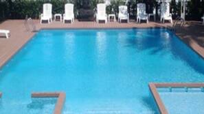 Una piscina al aire libre de temporada, tumbonas