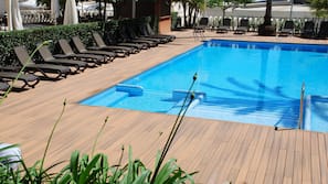 Una piscina al aire libre de temporada, tumbonas
