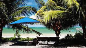 Na praia, areia branca, espreguiçadeiras, guarda-sóis