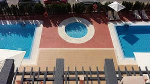 Una piscina al aire libre de temporada, sombrillas, tumbonas