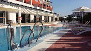Una piscina al aire libre de temporada, sombrillas, tumbonas