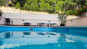 Una piscina al aire libre de temporada, sombrillas, tumbonas