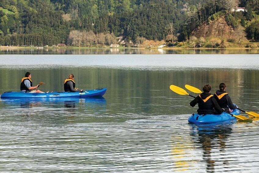 Dos personas kayakando en un lago tranquilo rodeado de árboles. 1