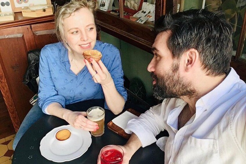 Two people sitting at a table with a plate of food, a glass of drink, and a menu. 3