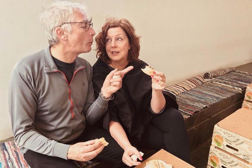 Two people sitting on a couch with a box of cereal boxes on the floor. 3