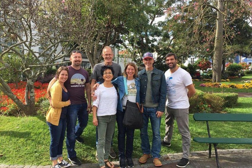 A group of people standing in a park with trees and flowers in the background. 5