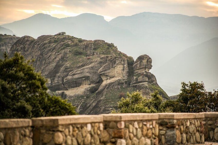 A mountainous landscape with prominent rock formations and a stone wall in the foreground. 5