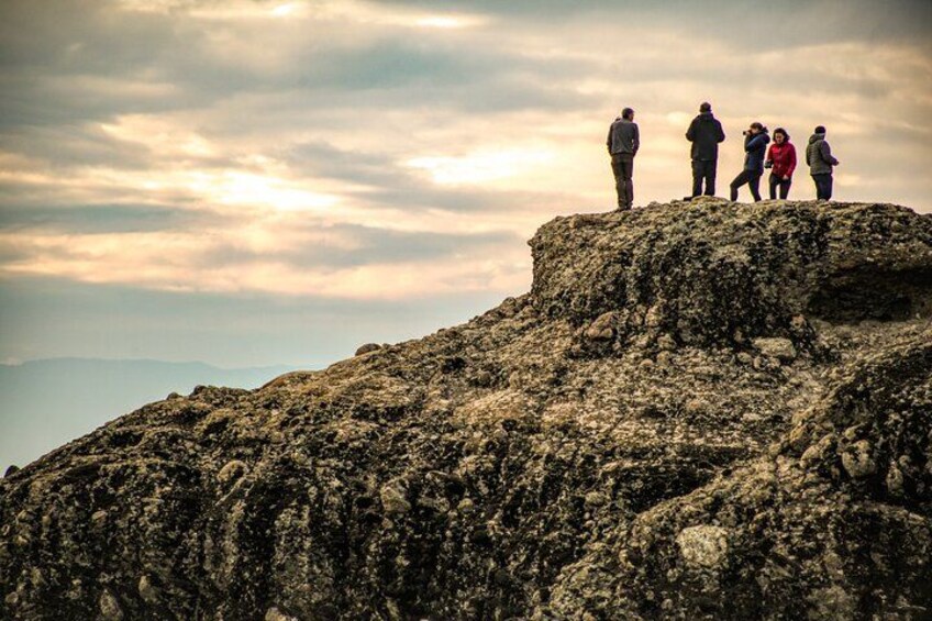 A group of people standing on a rocky outcrop with a cloudy sky in the background. 3