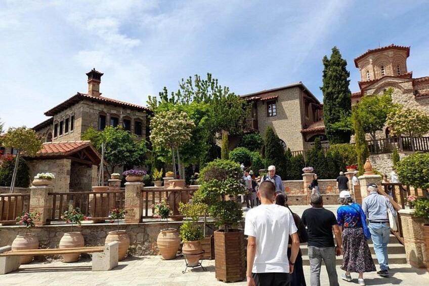 Un patio con edificios de piedra, plantas en macetas y un grupo de personas. 5