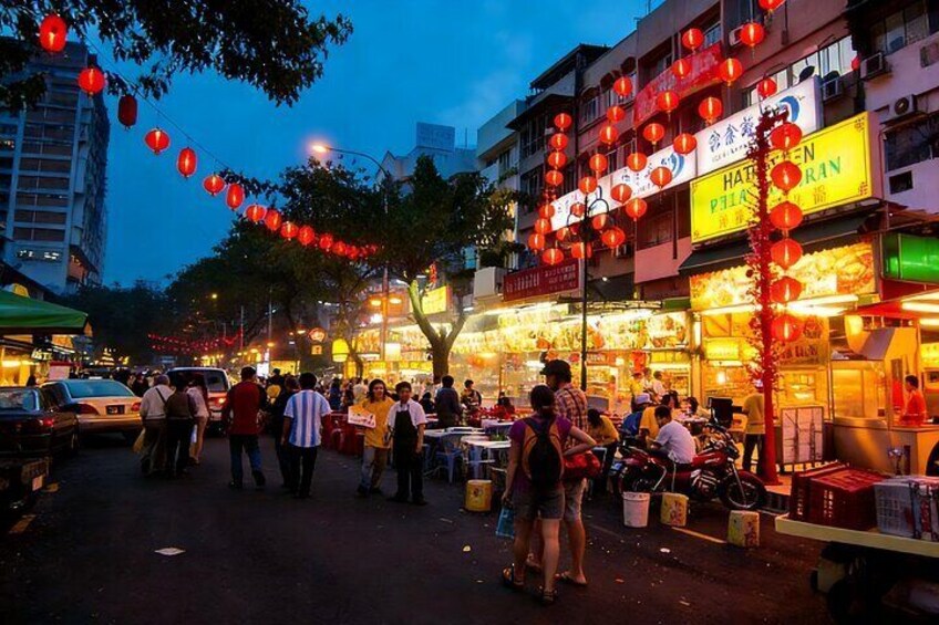 A bustling street market at dusk with red lanterns, food stalls, and people shopping. 4