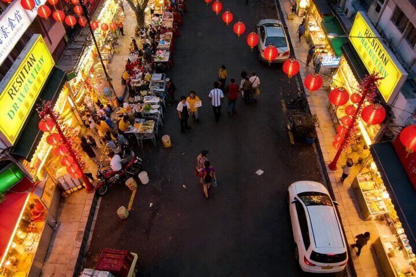 A bustling street market with food stalls and red lanterns. 3