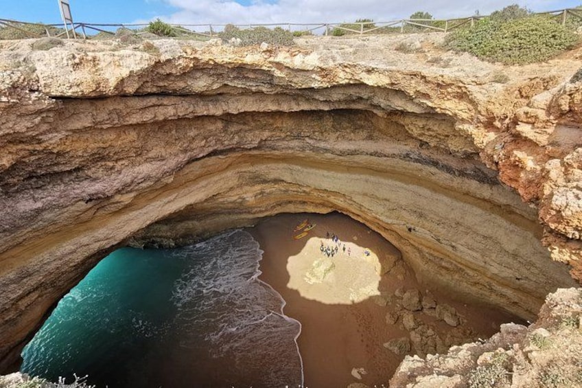 Eine natürliche Felsformation mit einer Höhle, einem Sandstrand und einem türkisfarbenen Becken. 5