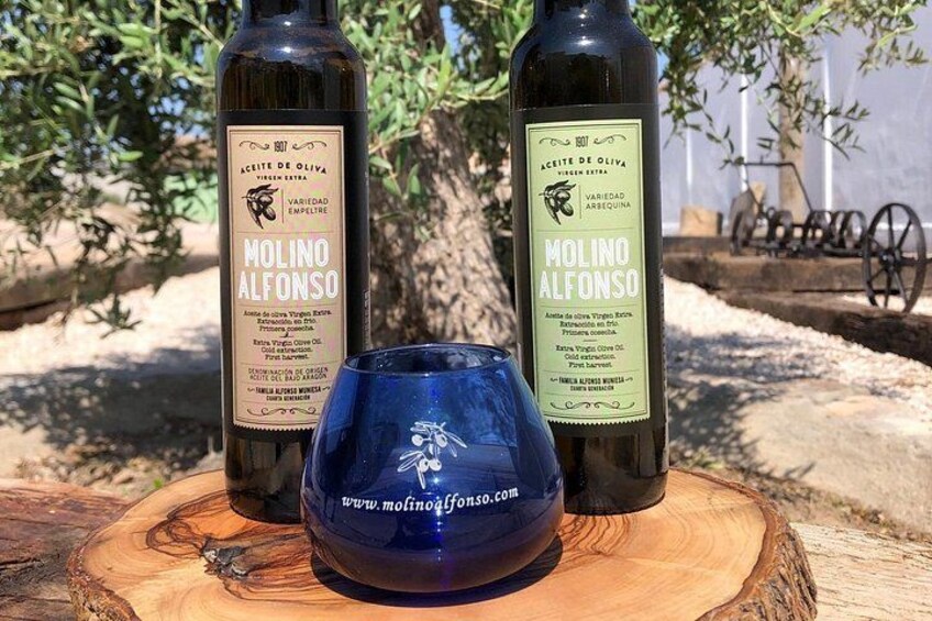 Two bottles of Molino Alfonso wine and a blue glass on a wooden surface. 5