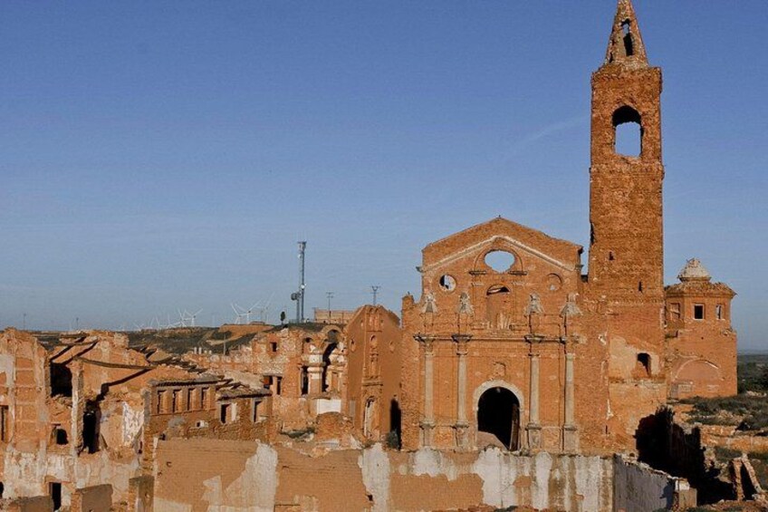 A historic church with a bell tower, partially ruined walls, and a clear sky. 2