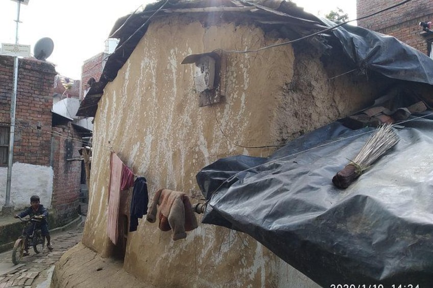 A weathered building with clothes hanging on a line, a broom, and a satellite dish on the roof. 1