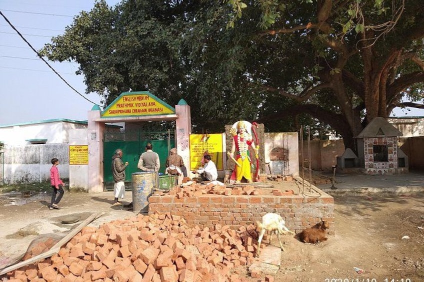 A temple entrance with a sign, a tree, and people around. 5