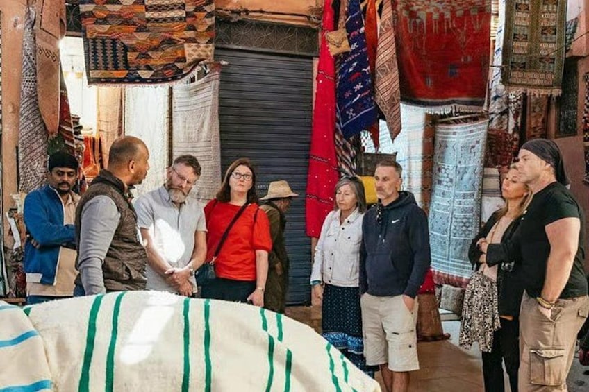 Un grupo de personas en un mercado con una variedad de textiles y telas a la vista. 2