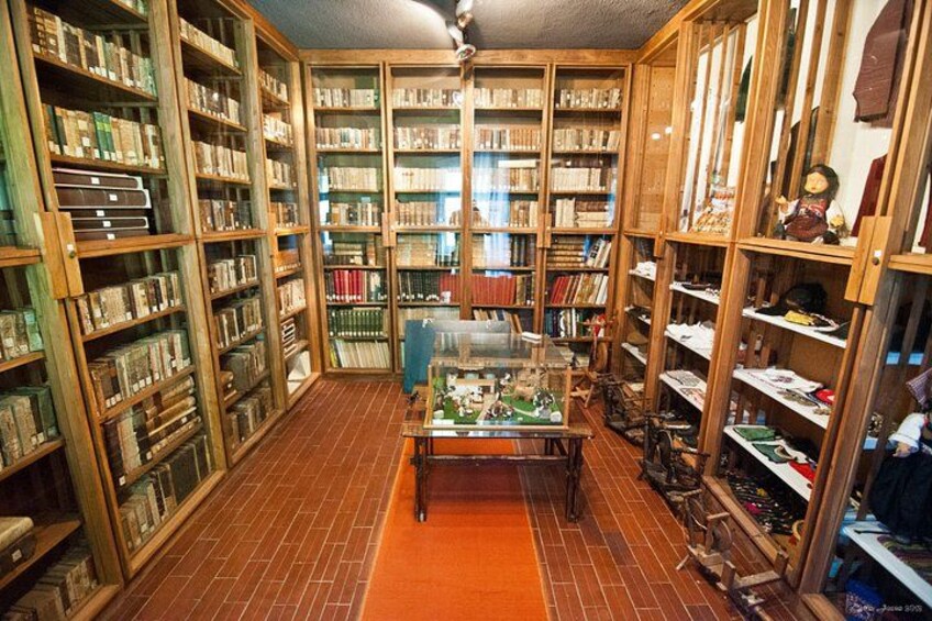 Een bibliotheek met houten boekenkasten vol boeken en een vitrine met modeltreinen. 2