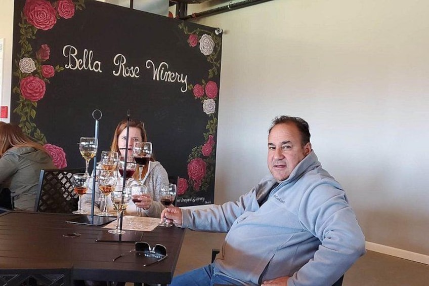 Un hombre sentado a una mesa con copas de vino y un menú en la bodega Bella Rose. 3
