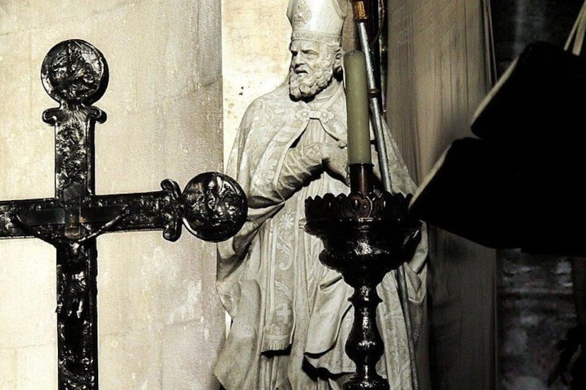 A statue of a robed figure with a candle holder in front. 3