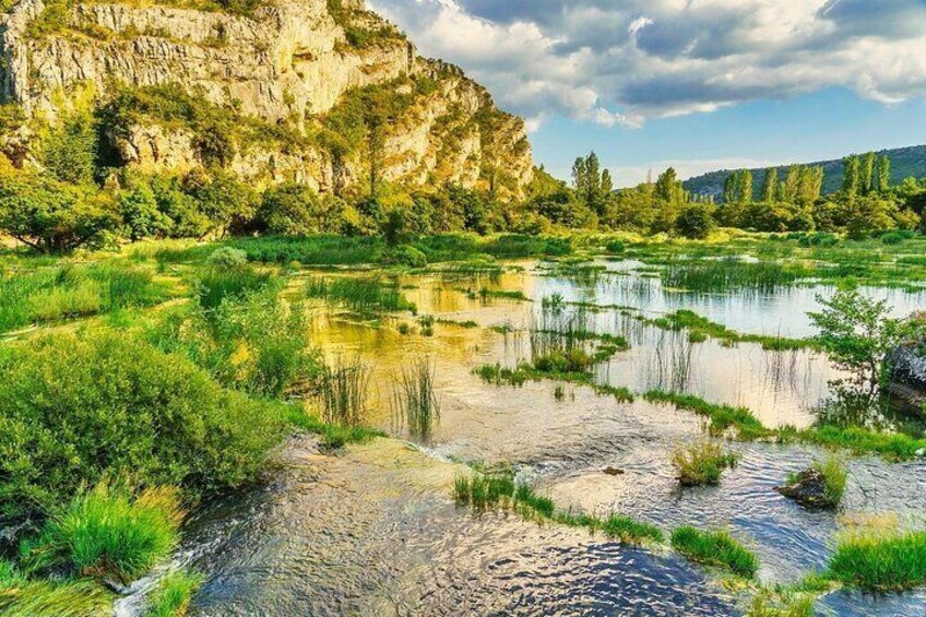 A river with surrounding greenery and a rocky cliff. 3