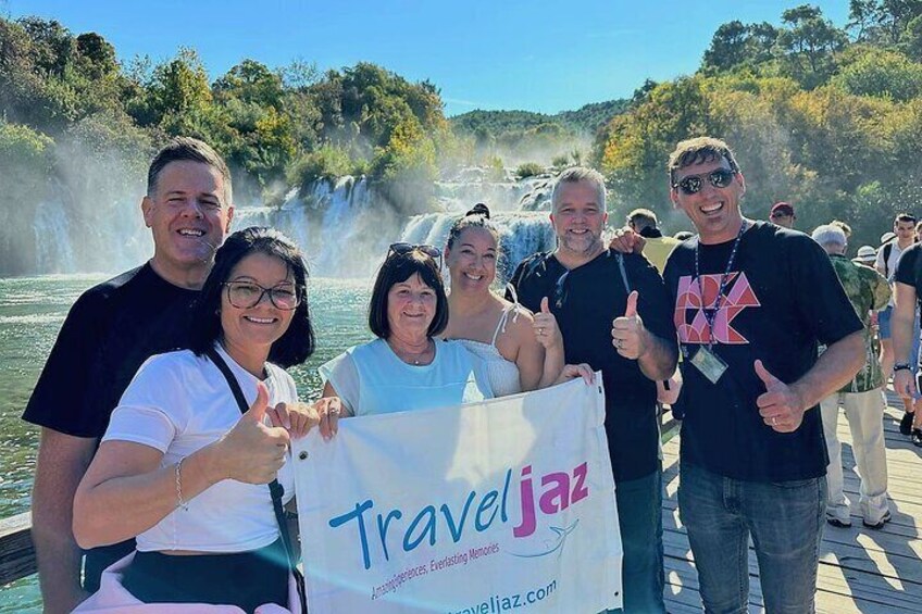 A group of people on a boat with a waterfall in the background. 1