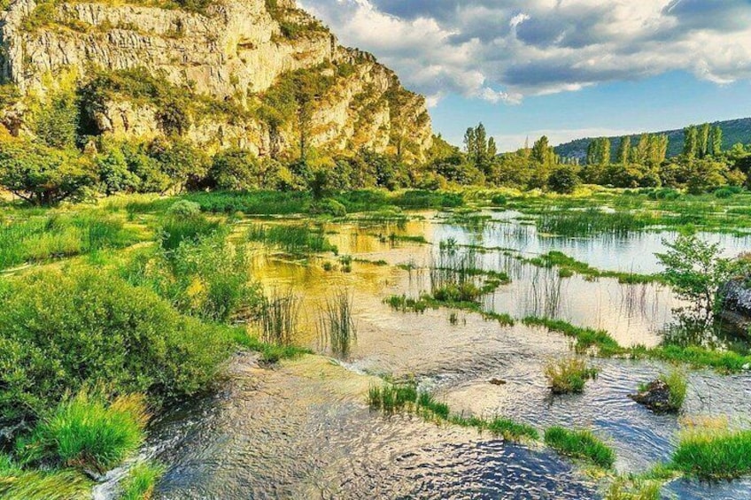 A river with surrounding greenery and a rocky cliff. 3
