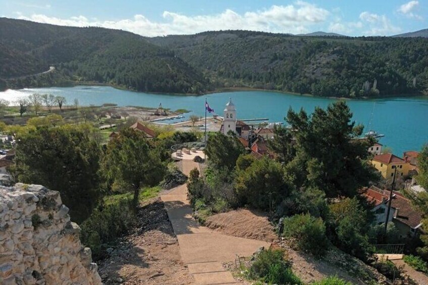 A coastal town with a church, a body of water, and surrounding hills. 4
