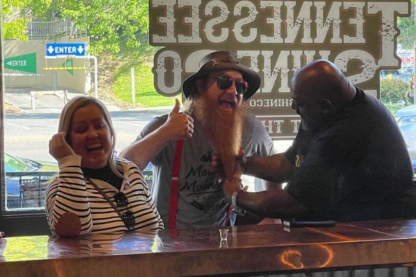 A bar counter with a person holding a drink and another person sitting at the bar. 2