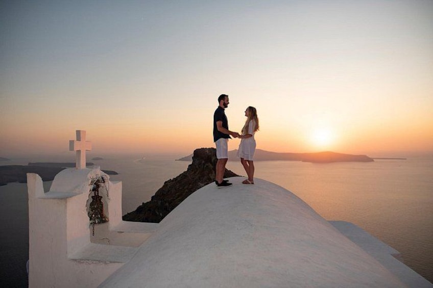 A couple standing on a white cliff overlooking the sea at sunset. 2