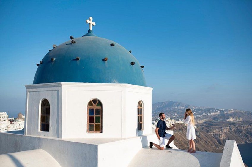 A white building with a blue dome and a cross on top, overlooking a mountainous landscape. 4