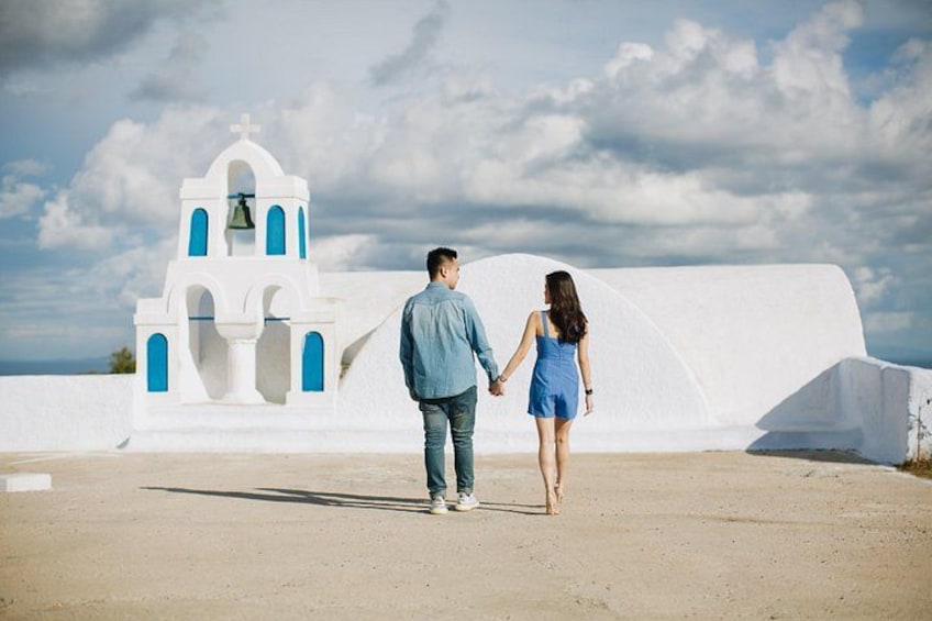 A couple walking on a beach with a white church in the background. 5