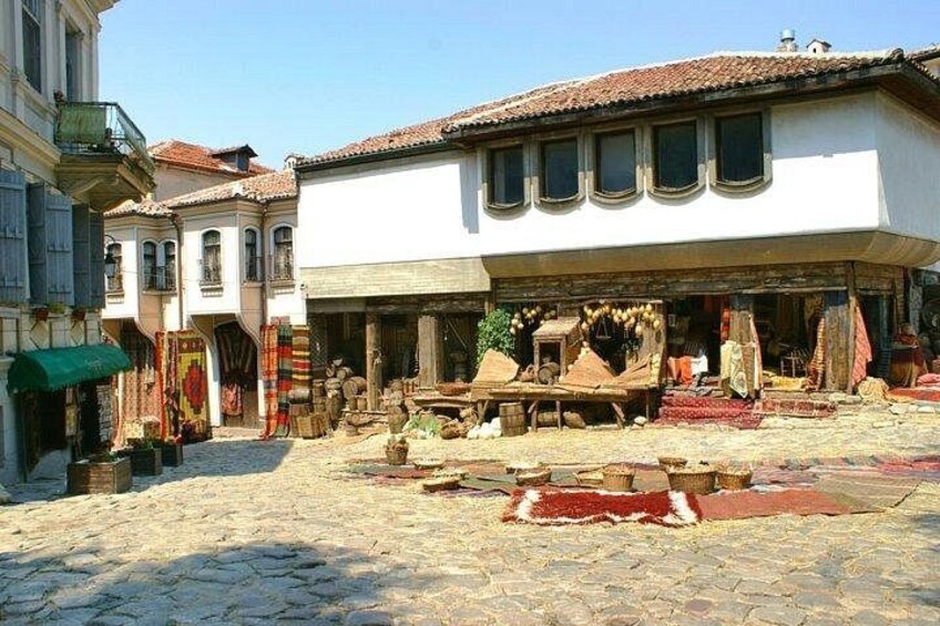 A cobblestone street with a shop displaying textiles and furniture. 1