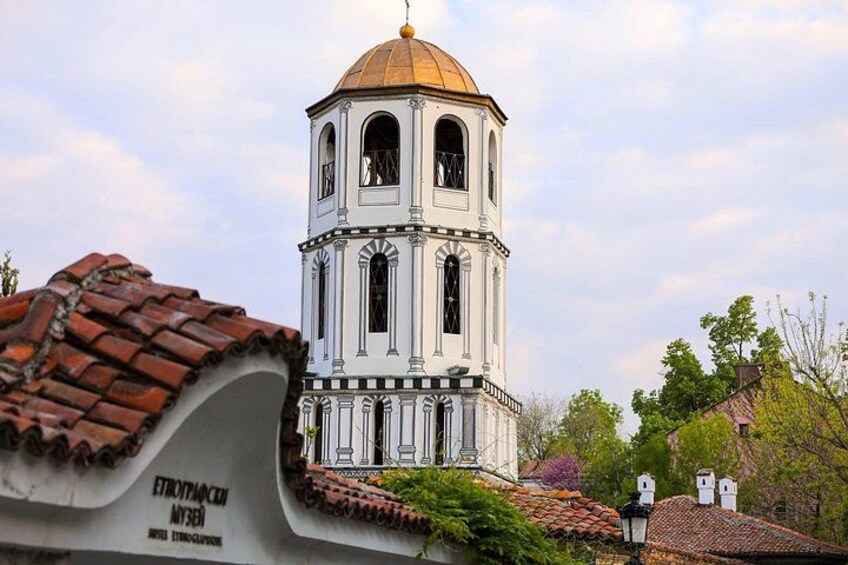 A white bell tower with a golden dome, surrounded by red-tiled roofs and greenery. 3