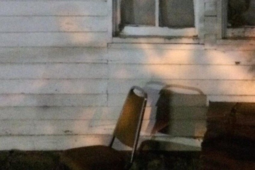 A wooden house with a porch and a chair. 3