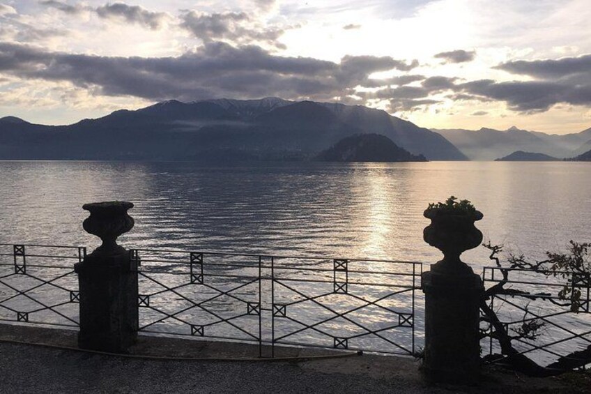 A lake with mountains in the background, a fence, and two stone urns. 2