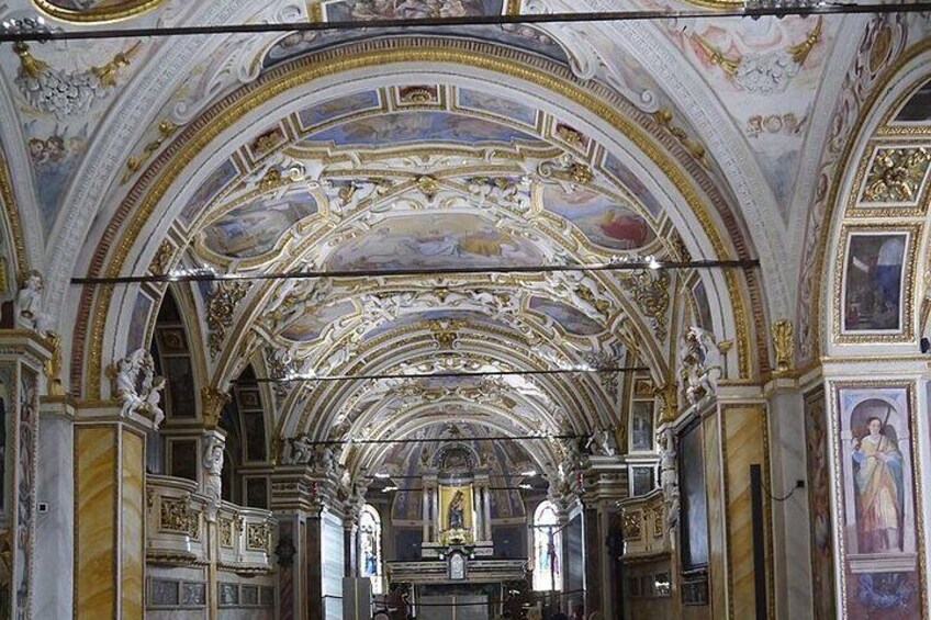 An ornate church interior with detailed frescoes, gold accents, and a central altar. 1