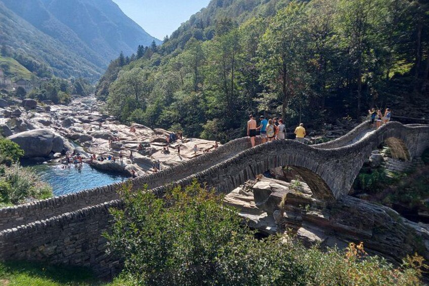A stone bridge over a river, surrounded by lush greenery and mountains. 2