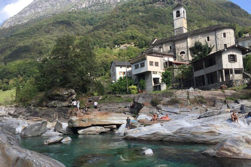 A historic building with a tower, surrounded by a rocky landscape and a clear water body. 5