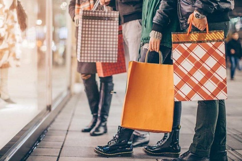 Människor går på en trottoar, och några av dem bär på shoppingpåsar. 5