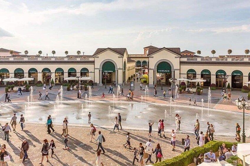 A public square with fountains, people walking, and storefronts. 4