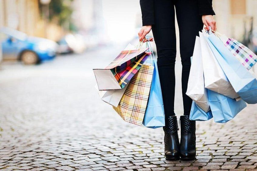 En person som bär på shoppingpåsar på en kullerstensgata. 4