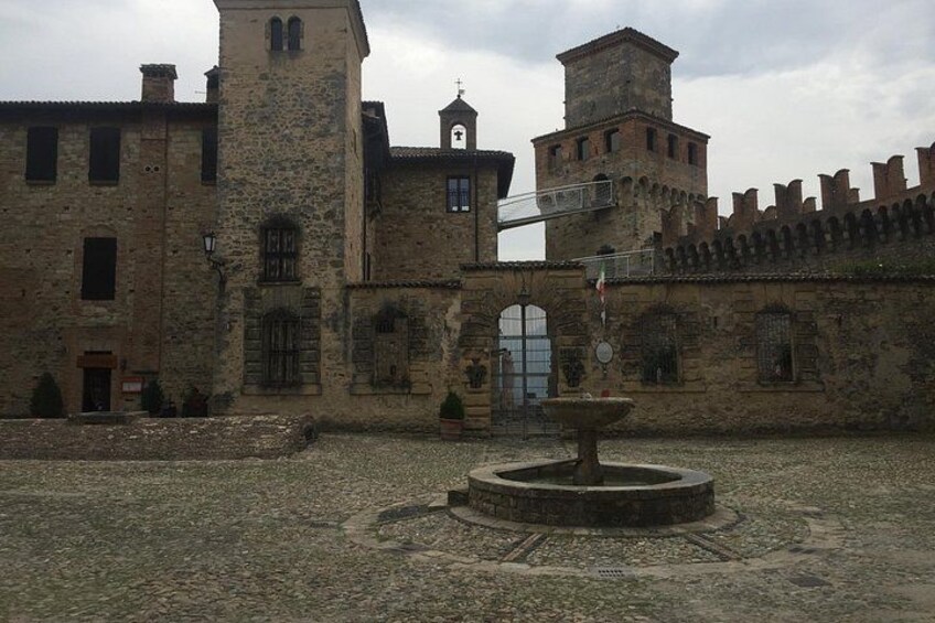 Ein historisches Steinhaus mit einem Turm, einer Fontäne und einer befestigten Mauer. 3