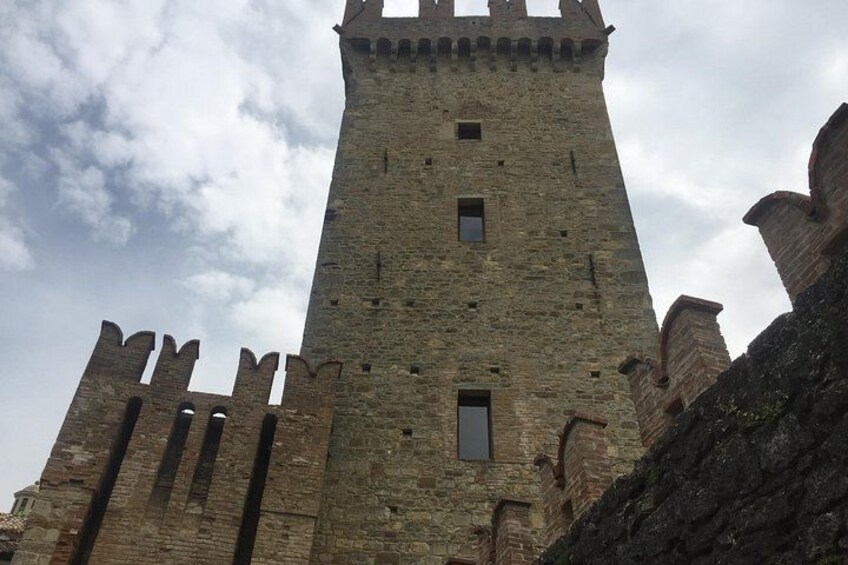 Ein hoher, steinerner Turm mit Zinnen, einem schmalen Fenster und einer Steinmauer. 4
