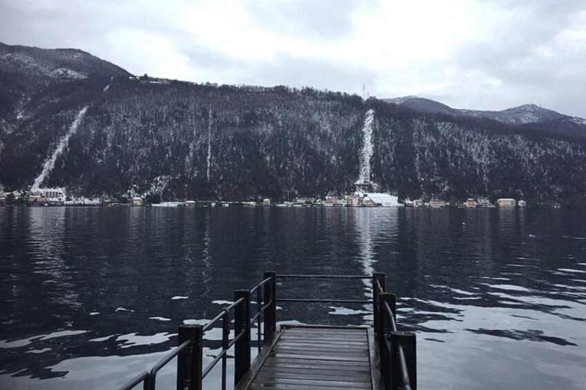 A lake with a wooden dock, a mountain in the background, and a waterfall. 4