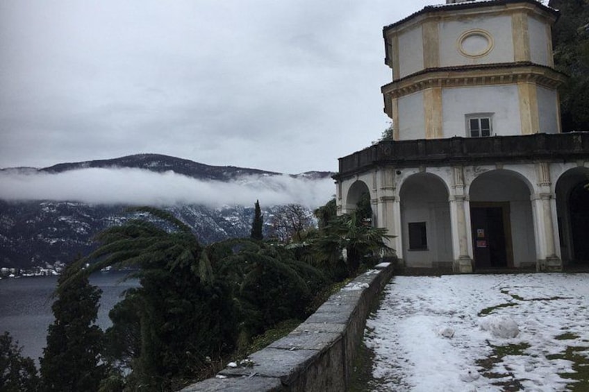 A historic building with arched windows and a tower, surrounded by snow-covered ground and a mountainous backdrop. 3