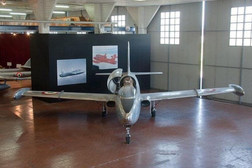 Un avión antiguo en un hangar con un panel de exhibición al fondo. 3