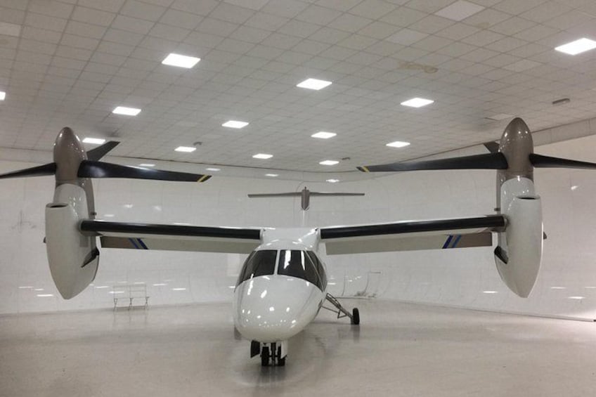 Un helicóptero dentro de un hangar con interior blanco y techo cuadriculado. 2